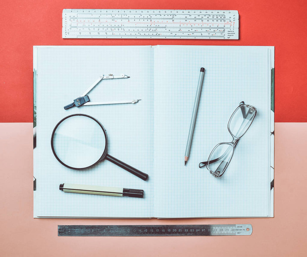 A large notebook for notes and drafting with stationery objects for a student. Ruler, marker, pencil, magnifying glass, compasses, glasses. Top view. - Foto, Imagen