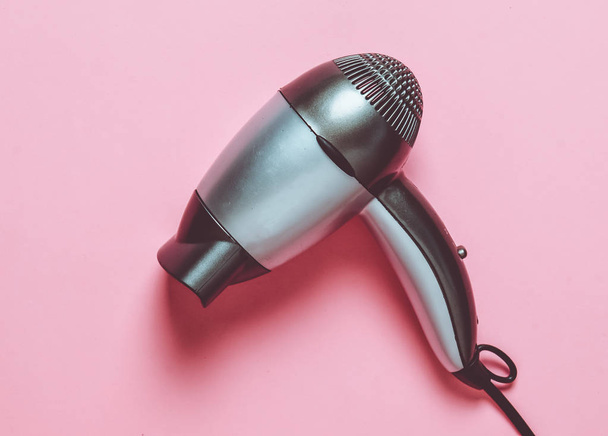 Gray plastic hair dryer on a pink pastel background. Hair care. - Foto, immagini