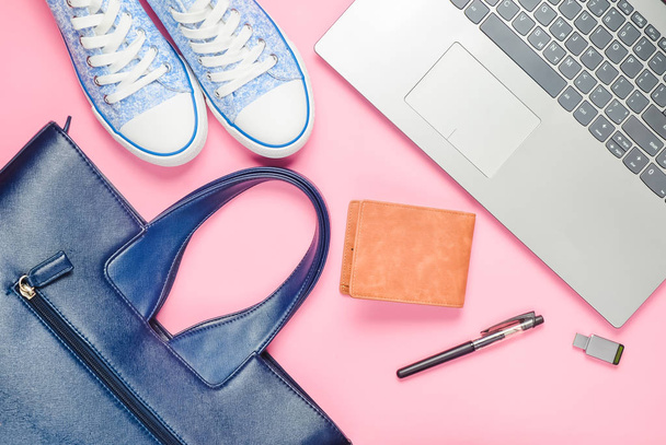 Ordinateur portable, clé USB et accessoires féminins à la mode sur un fond rose : sac, portefeuille, baskets, sac. Vue de dessus. Pose plate
. - Photo, image