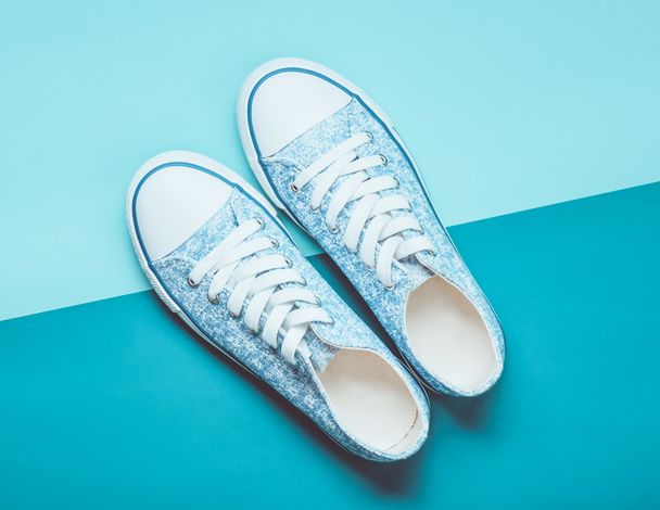 Fashionable women's sneakers with white laces from the 80s on a blue pastel background. Top view. - Photo, Image