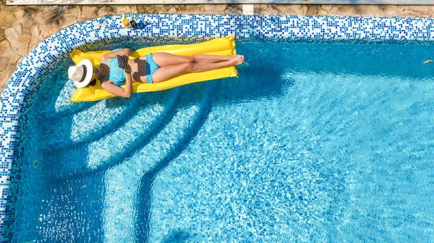 Piękna młoda dziewczyna relaks w basenie pływa na nadmuchiwany materac i ma zabawy w wodzie na rodzinne wakacje, tropikalnych holiday resort, antenowe drone widok z góry - Zdjęcie, obraz