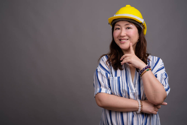 Зрелая азиатская предпринимательница-строитель в каске
 - Фото, изображение