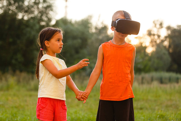 Kleines Mädchen mit Bruder in Virtual-Reality-Headsets spielt gemeinsam im Park - Foto, Bild