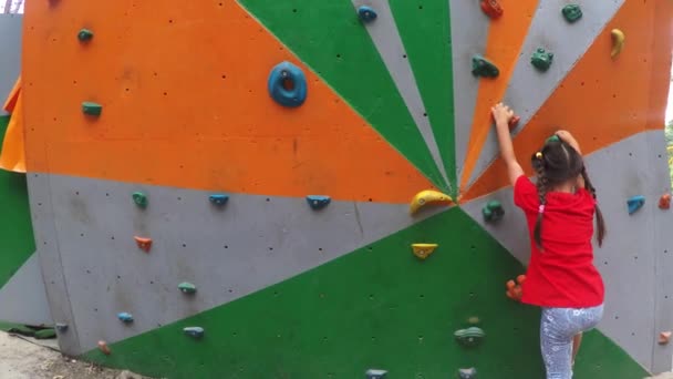Sportieve meisje kunstmatige boulder klimmen op praktische muur in park - Video
