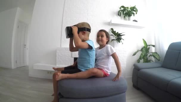 Brat i siostra za pomocą okulary wirtualnej rzeczywistości w salonie  - Materiał filmowy, wideo