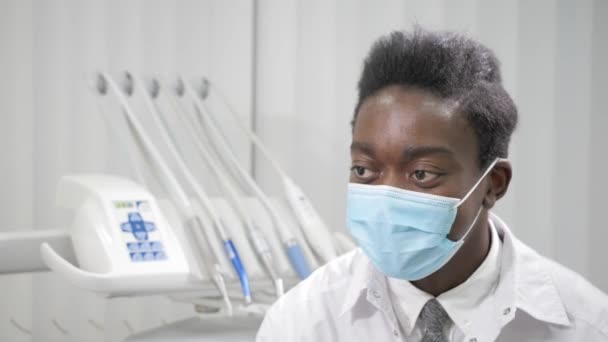 Jonge African American mannelijke arts-tandarts in medische masker. Geneeskunde, gezondheid, stomatologie concept. tandarts voert inspectie en concludeert - Video