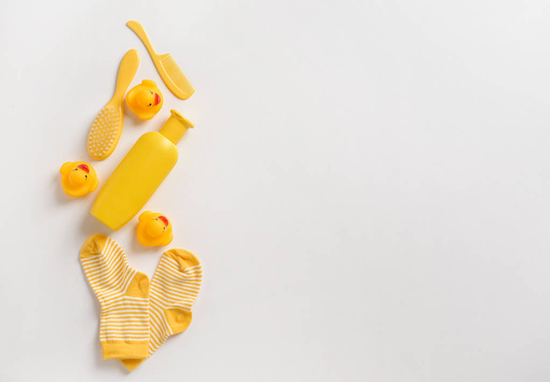 Косметика для ванн, резиновые утки и детские носки на белом фоне
 - Фото, изображение