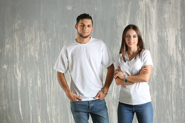 Mladý muž a žena ve stylové trička na šedém pozadí - Fotografie, Obrázek
