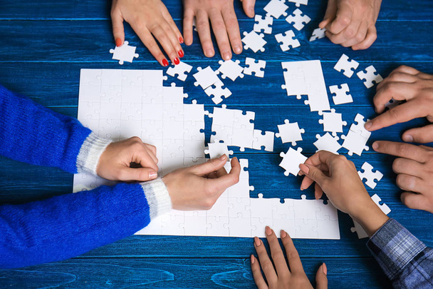 Skupina lidí, kteří dělají puzzle na stole - Fotografie, Obrázek