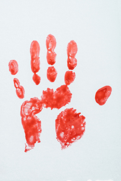 вид сверху на отпечаток крови, нанесенный рукой на белой поверхности
 - Фото, изображение