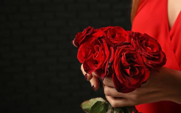 Woman with bouquet of beautiful roses on dark background, closeup - Photo, Image