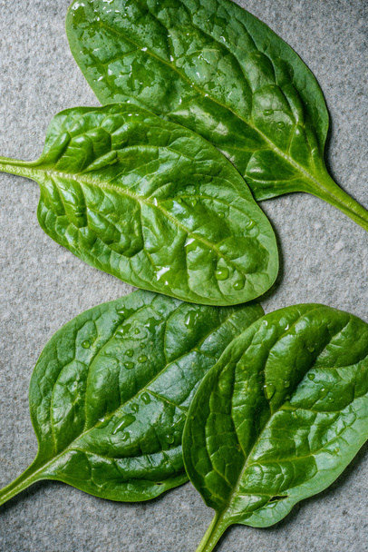 Top view of green and fresh picked spinach leaves on grey background - Zdjęcie, obraz