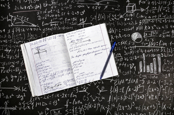 ein geschriebenes Notizbuch mit Stift auf dem Hintergrund der Tafel mit Beispielen und Formeln - Foto, Bild