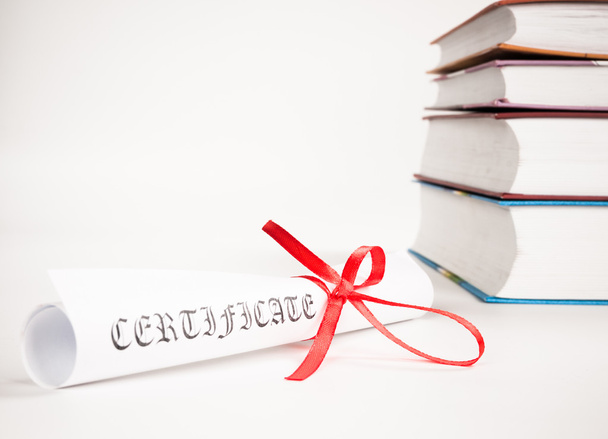 Diploma with red ribbon and books - Foto, Imagen