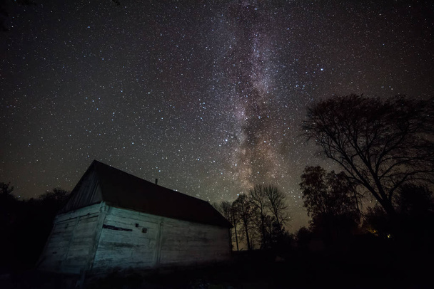 Old wooden hut and the Milky Way. Night photo. - 写真・画像