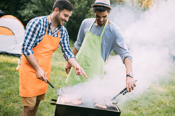 Cheerful friends spending time in nature and having barbecue - Foto, Imagem