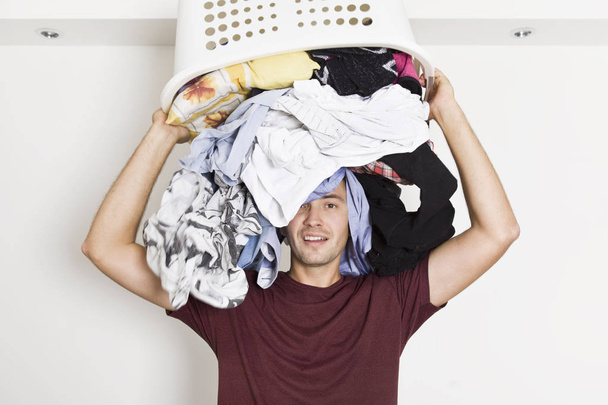 Frustrated young man with full of clothes on his head. Laundry time - Foto, immagini