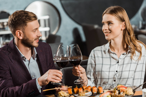 Jovem casal adulto apaixonado clinking enquanto janta no restaurante
 - Foto, Imagem