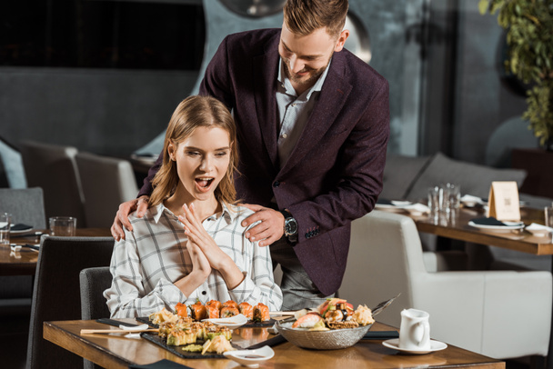 Handsome man with his happy surprised girlfriend in restaurant  - Photo, Image