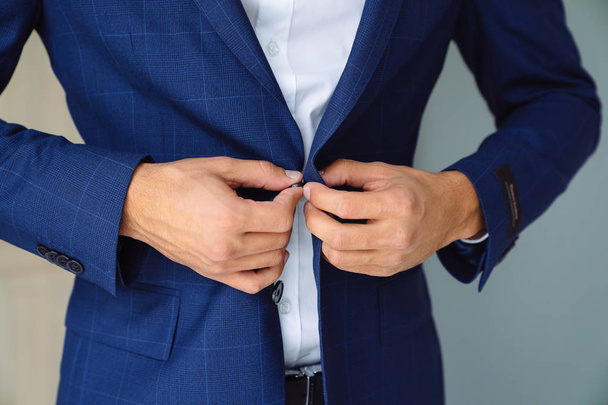 Крупный бизнес стильный мужчина застегивает свою голубую куртку, стоя в стильном офисе с дизайнерским ремонтом
. - Фото, изображение