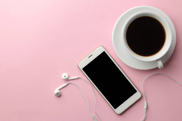 ヘッドフォンと明るいピンクの背景のコーヒー カップ白スマート フォン。上からの眺め - 写真・画像