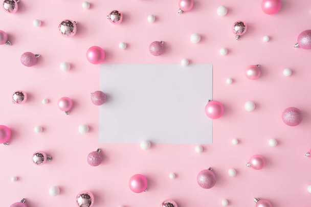 Kreative Weihnachtskomposition aus Papierkarton in der Mitte und Kugeln auf rosafarbenem Hintergrund. Neujahrskonzept   - Foto, Bild