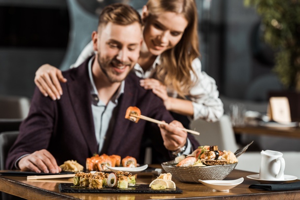 Szczęśliwa para atrakcyjne obiad i jedzenie smaczne sushi rolki w restauracji - Zdjęcie, obraz