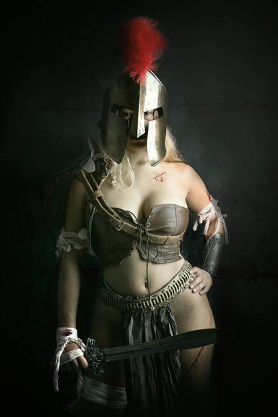 Oude vrouw krijger of gladiator poseren in een donkere achtergrond - Foto, afbeelding