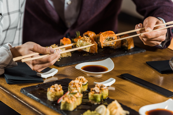レストランで箸で寿司を食べている人々 のビューをトリミング - 写真・画像