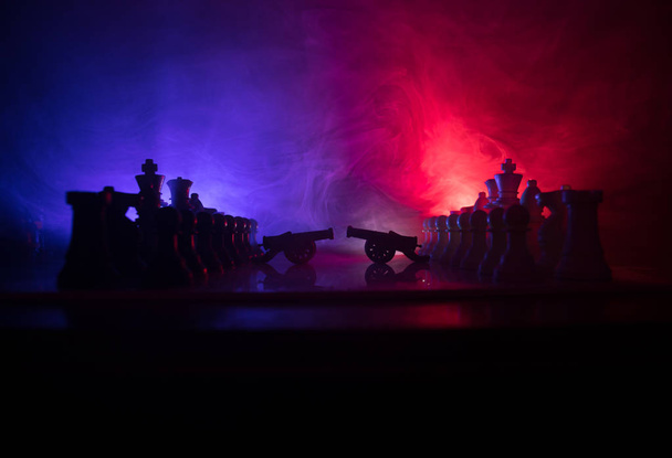 Middeleeuwse slag scène met twee kanonnen op een schaakbord. Schaken bordspel concept van bedrijfsideeën en concurrentie en strategie ideeën Chess cijfers op een donkere achtergrond met rook en mist. - Foto, afbeelding