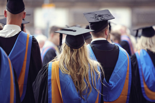 Afgestudeerden bij Universiteit graduatie ceremonie dragen mortarboard en jurk - Foto, afbeelding