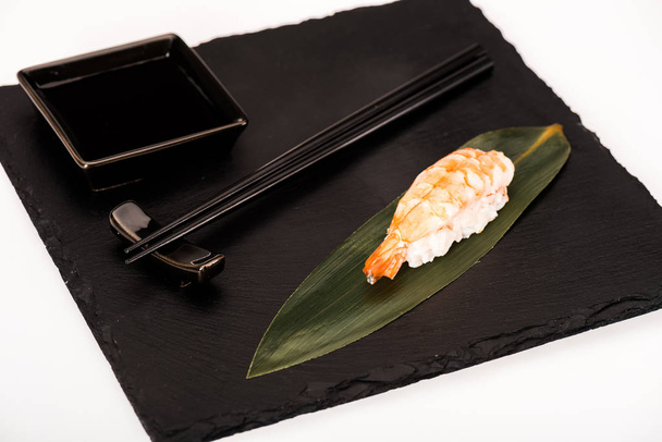 Nigiri sushi with shrimp served with chopsticks and soy sauce on black slate - Фото, изображение