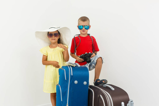 Frère et sœur avec bagages de voyage posant sur fond blanc
  - Photo, image