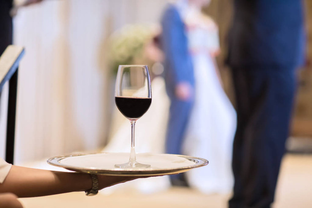 Kellner karrt Teller mit Rotweingläsern. Brille auf. Weingläser. Kellnerin mit einer Tasse Champagner und Weingläsern bei festlichen Anlässen, Feiern oder Hochzeiten - Foto, Bild