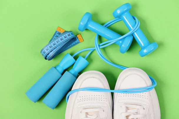 Sneakers with skipping rope and tape on green background. - Foto, immagini