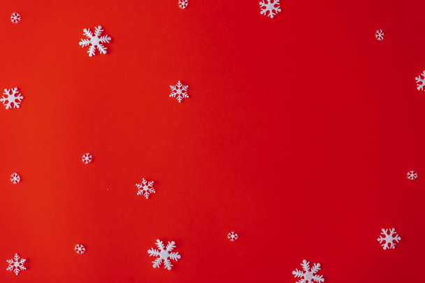 Fondo rojo de Navidad con copos de nieve blancos. Flat lay Año nuevo patrón mínimo
. - Foto, imagen