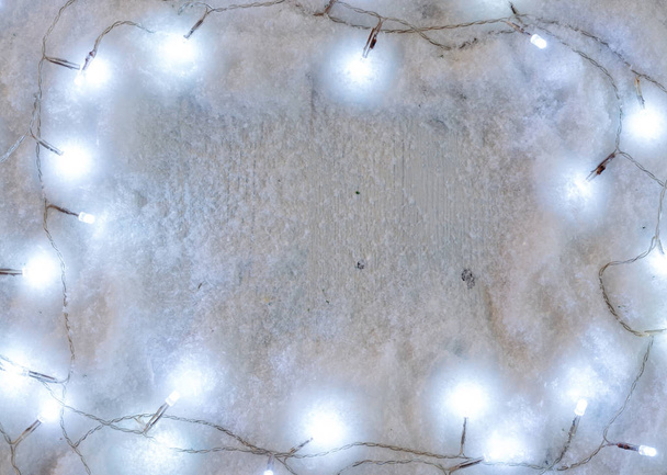 Snowy New Year background composition with decorative Christmas  lights. Flat lay  - Photo, Image