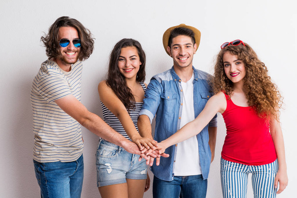 Portrait of joyful young group of friends putting their hands together in a studio. - Fotoğraf, Görsel