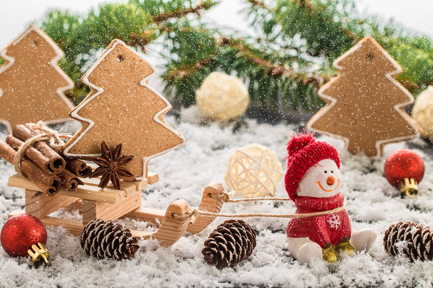 Boneco de neve em um boné vermelho na mesa de madeira. Composição de Natal ou Ano Novo com presentes e biscoitos de gengibre. Composição de férias de inverno
.  - Foto, Imagem
