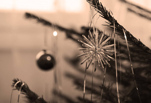 Schließen Foto eines Zweiges des Weihnachtsbaums mit einem Strohstern in Ockertönen dekoriert - Foto, Bild