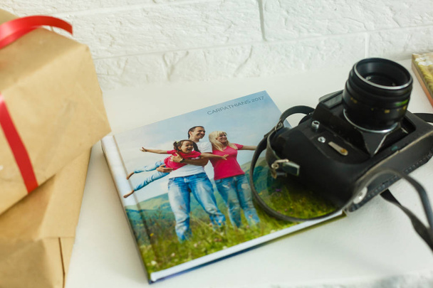 Rodzinna książka fotograficzna leżąca na białym stole - Zdjęcie, obraz