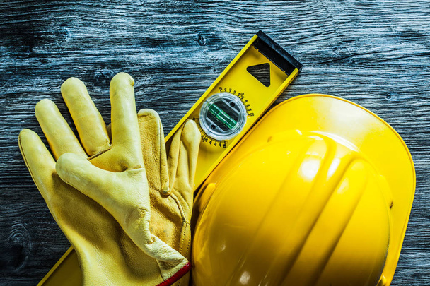 Stavební úrovně bezpečnosti rukavice budování helmu na dřevěné desce. - Fotografie, Obrázek