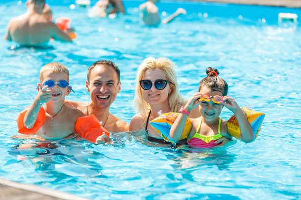 fröhliche Familie mit zwei Kindern, die Spaß im Schwimmbad haben - Foto, Bild