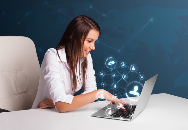 Young lady sitting at desk and typing on laptop with social netw - Foto, Imagen