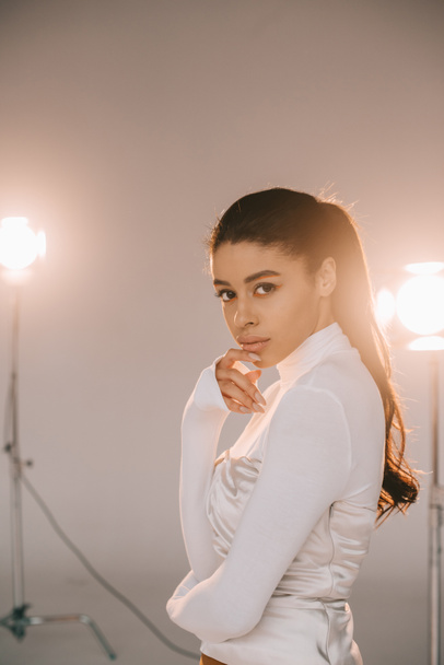 stylish young woman in white turtle neck posing in studio with spotlights - Foto, immagini