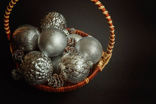 Navidad Año Nuevo Composición con bolas de plata Conos de pino en la cesta Fondo negro Decoración de vacaciones a la tradición rusa
 - Foto, Imagen