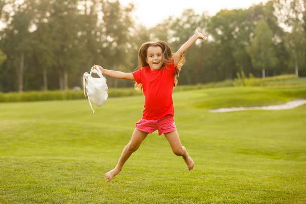 Niña morena divirtiéndose en campo de golf verde
  - Foto, Imagen