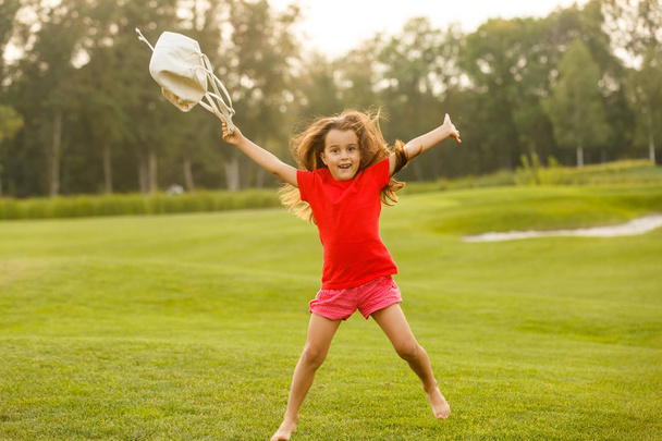 Petite fille brune s'amuser sur un terrain de golf vert
  - Photo, image