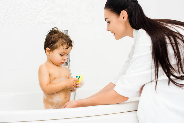 Mother washing son with yellow bath toy  - Foto, imagen