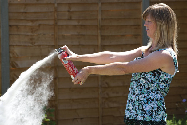 Femme utilisant un extincteur à poudre sèche
 - Photo, image